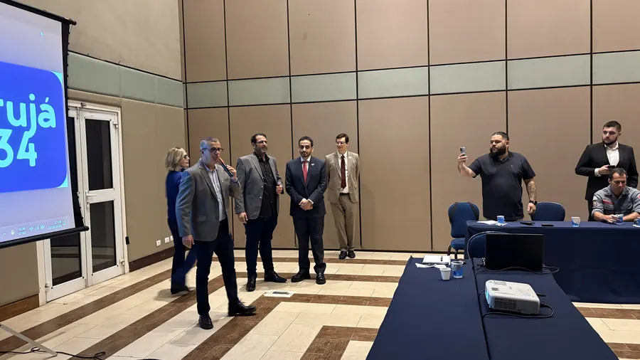 Convidados em pé diante do telão do Guarujá 2034 durante reunião do Movimento